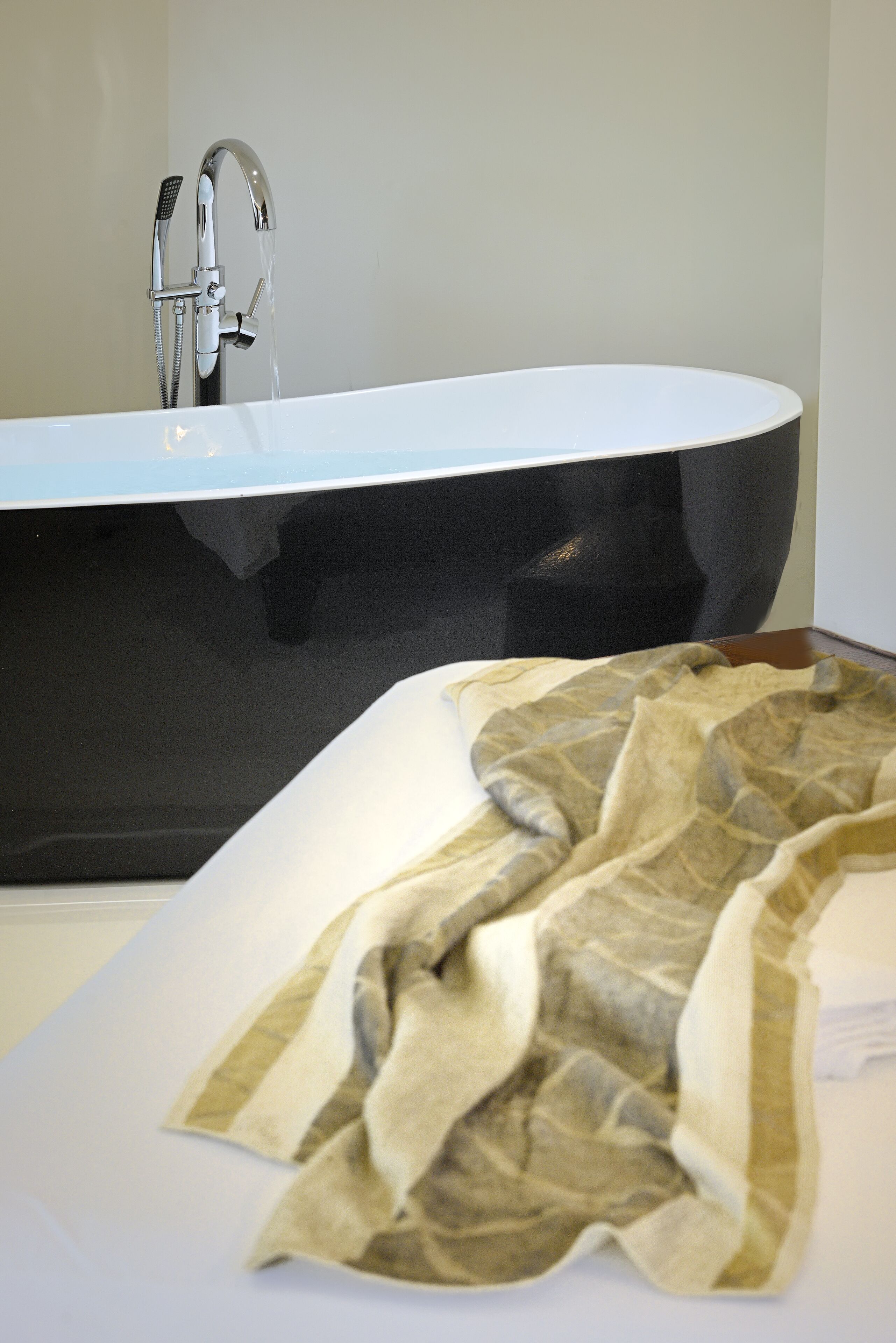 A modern bathroom with a black bathtub and a shower head.
