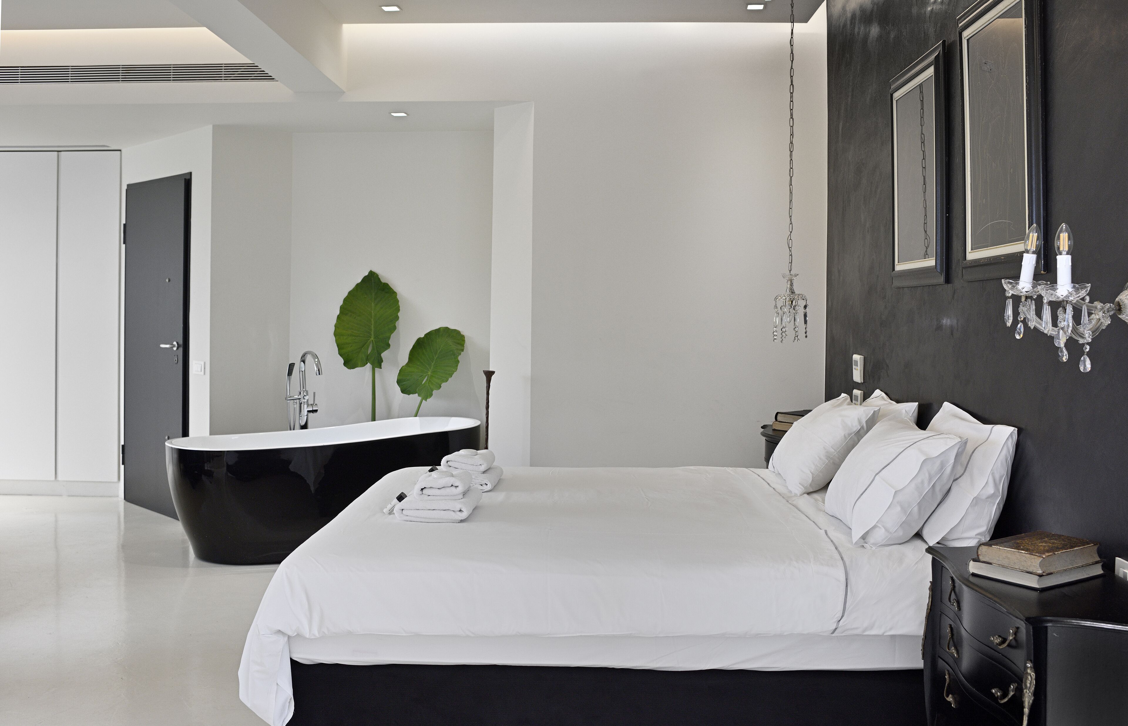 Een moderne slaapkamer met een groot bed, een zwart bad en een spiegel aan de muur.