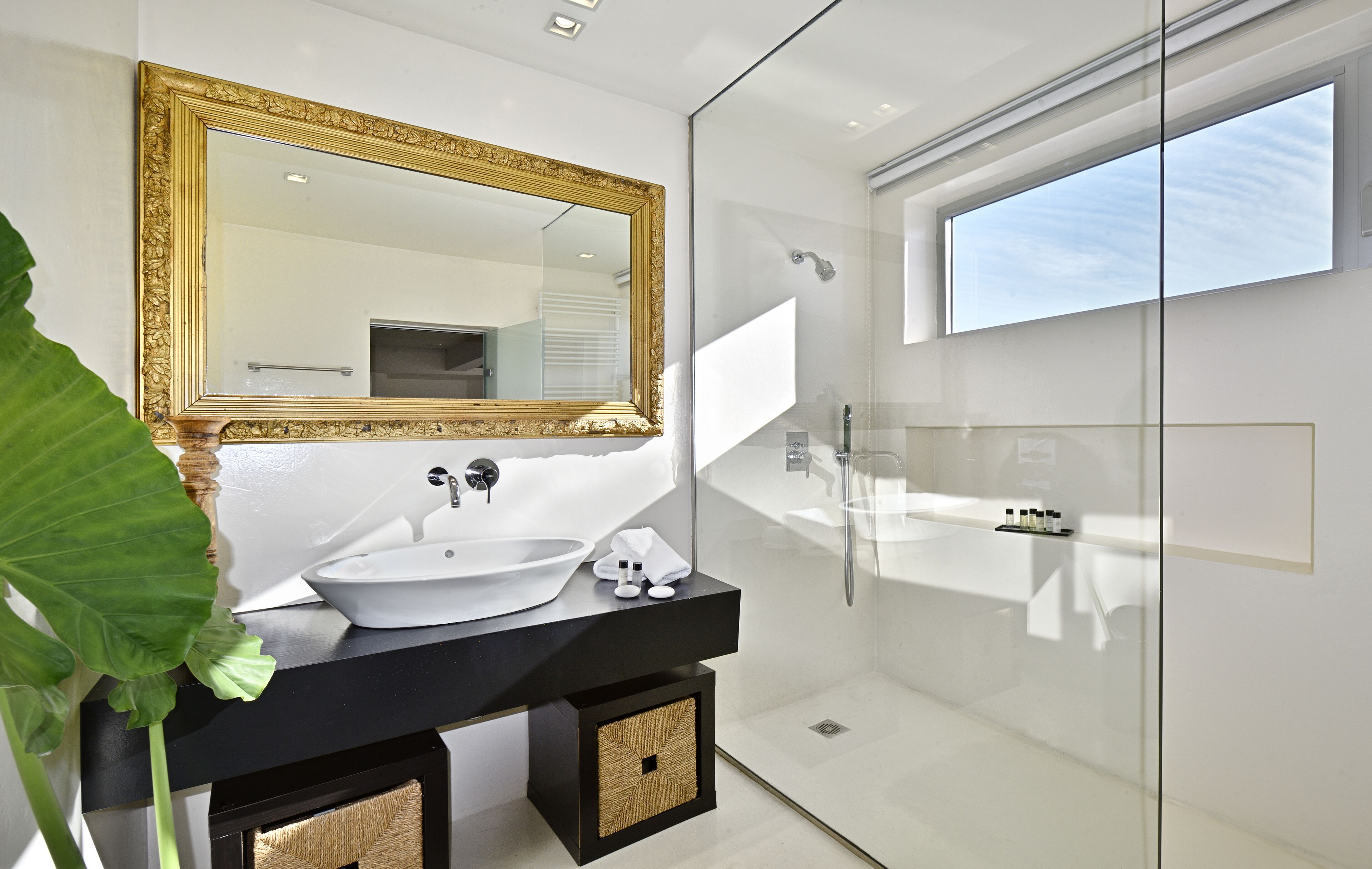 A modern bathroom with a large mirror, white sink, and glass shower enclosure.