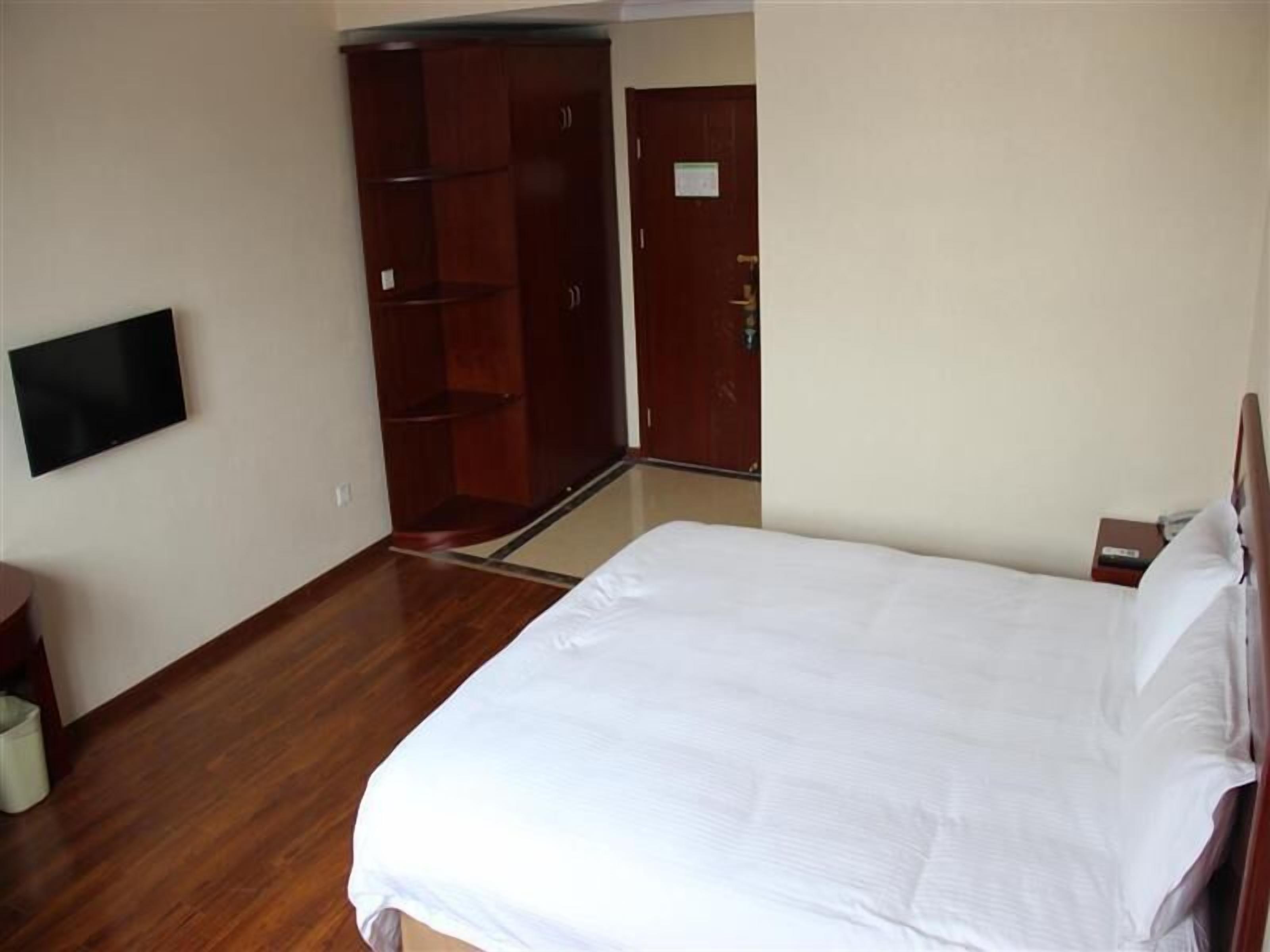 Une chambre à coucher avec un lit, une armoire, un téléviseur et une porte.