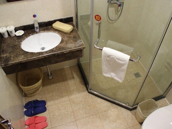 Un baño con lavamanos, cabina de ducha de vidrio y una toalla colgada en la puerta.