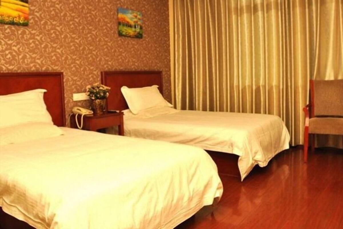 Une chambre d’hôtel avec deux lits, un plancher en bois et un rideau à la fenêtre.