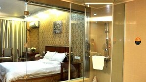 A hotel room with a glass-enclosed shower, a bed, a nightstand, and a patterned wall. - Greentree Inn Suzhou Wangting Zhanwang Business Hotel (Suzhou)