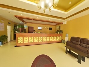 A reception area with a reception desk, a brown sofa, and a large decorative mirror. - Greentree Inn Shanghai Songjiang District Yanshou Road Li ta Express Hotel (Shanghai)