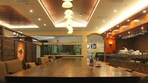 Un salón de conferencias con una larga mesa y múltiples sillas, una zona de bar con un cantinero, y un gran acuario al fondo.