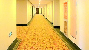Un largo y estrecho pasillo de hotel con piso alfombrado y puertas a ambos lados.