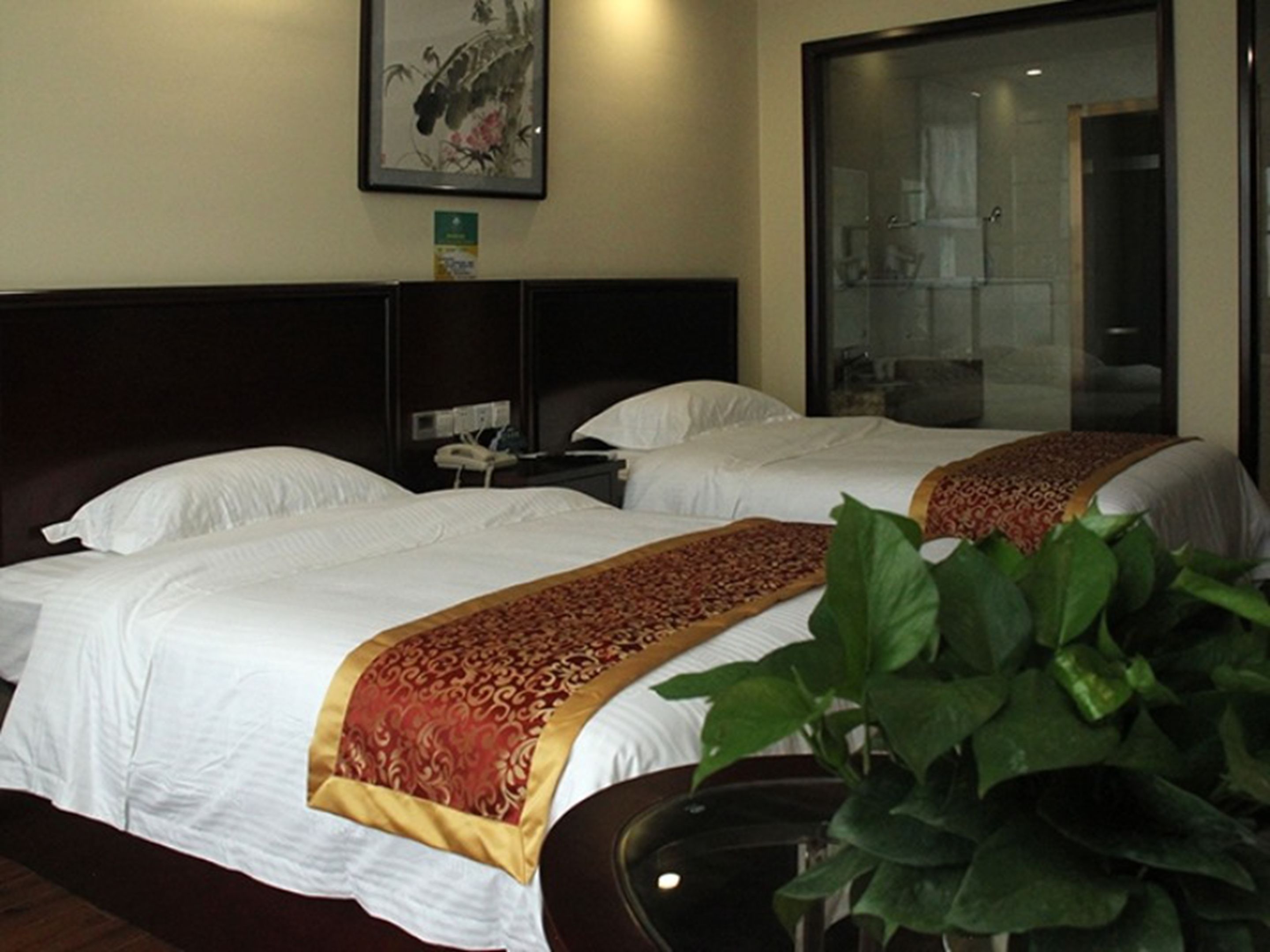 Habitación de hotel con dos camas, un ventanal grande y una planta en maceta.