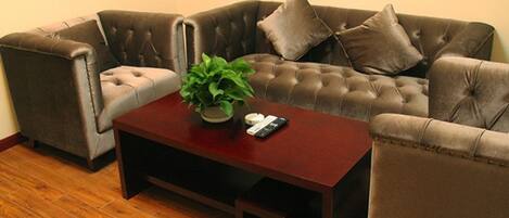 A living room with a brown sofa, a matching armchair, a wooden coffee table, and a potted plant.