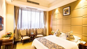A hotel room with a large bed, a desk with a chair, a small table with two chairs, a window with curtains, and a headboard with a picture. - GreenTree Inn JieYang Bus Terminal Station RongHua Avenue Hotel (Jieyang)