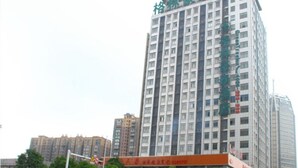 Un edificio de varios pisos con un letrero verde en la parte superior.