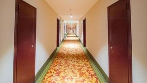 A long, narrow hotel corridor with wooden doors on either side and a carpeted floor. - GreenTree Inn Nantong Qidong Bus Station Express Hotel (Nantong)