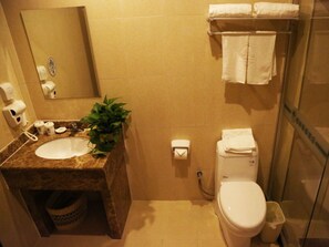 Un baño con lavamanos, espejo, inodoro y cabina de ducha de vidrio.