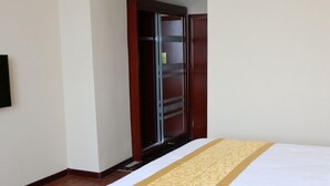 Hotellihuone, jossa on sänky, vaatekaappi ja peili.
