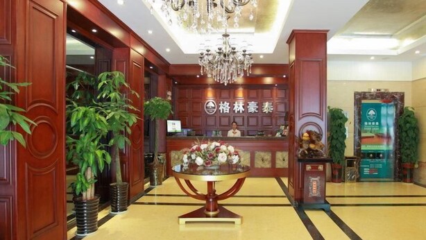 A hotel lobby with a reception desk, a chandelier, and potted plants. - GreenTree Inn Hefei Chenghuangmiao Hotel (Hefei)