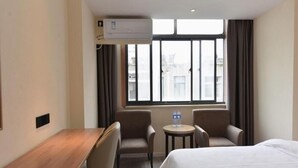 A hotel room with a bed, a desk, two chairs, a small table with water bottles, and a window with curtains. - GreenTree Inn Hefei Chenghuangmiao Hotel (Hefei)