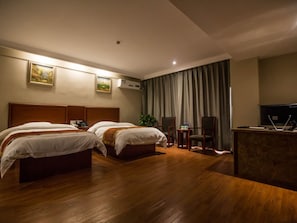 Une chambre d’hôtel avec deux lits, un bureau, une chaise et un téléviseur.