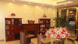A lobby with a fireplace, bookshelves, a round table with a floral centerpiece, and a glass door entrance. - GreenTree Inn Zhenjiang Danyang Wanshan Park Express Hotel (Zhenjiang)