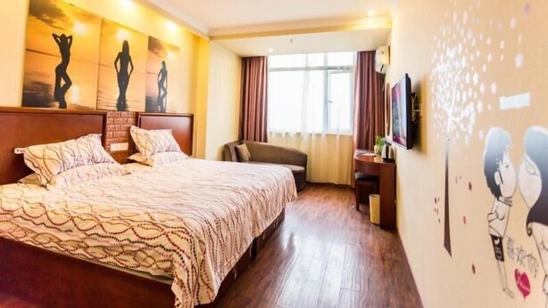A hotel room with a large bed, a desk with a chair, and artwork on the walls. - GreenTree Inn Zhenjiang Danyang Wanshan Park Express Hotel (Zhenjiang)