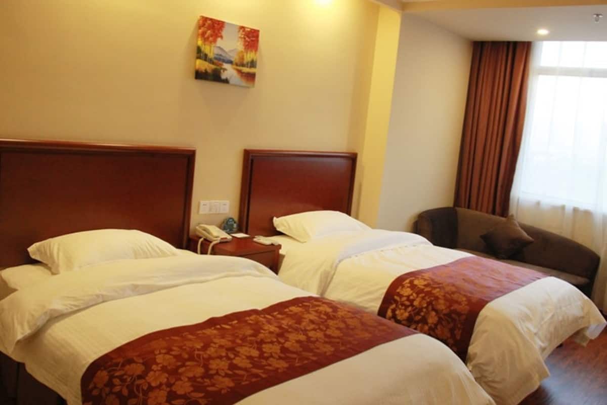 Une chambre d’hôtel avec deux lits, une table de chevet, une chaise et un tableau au mur.
