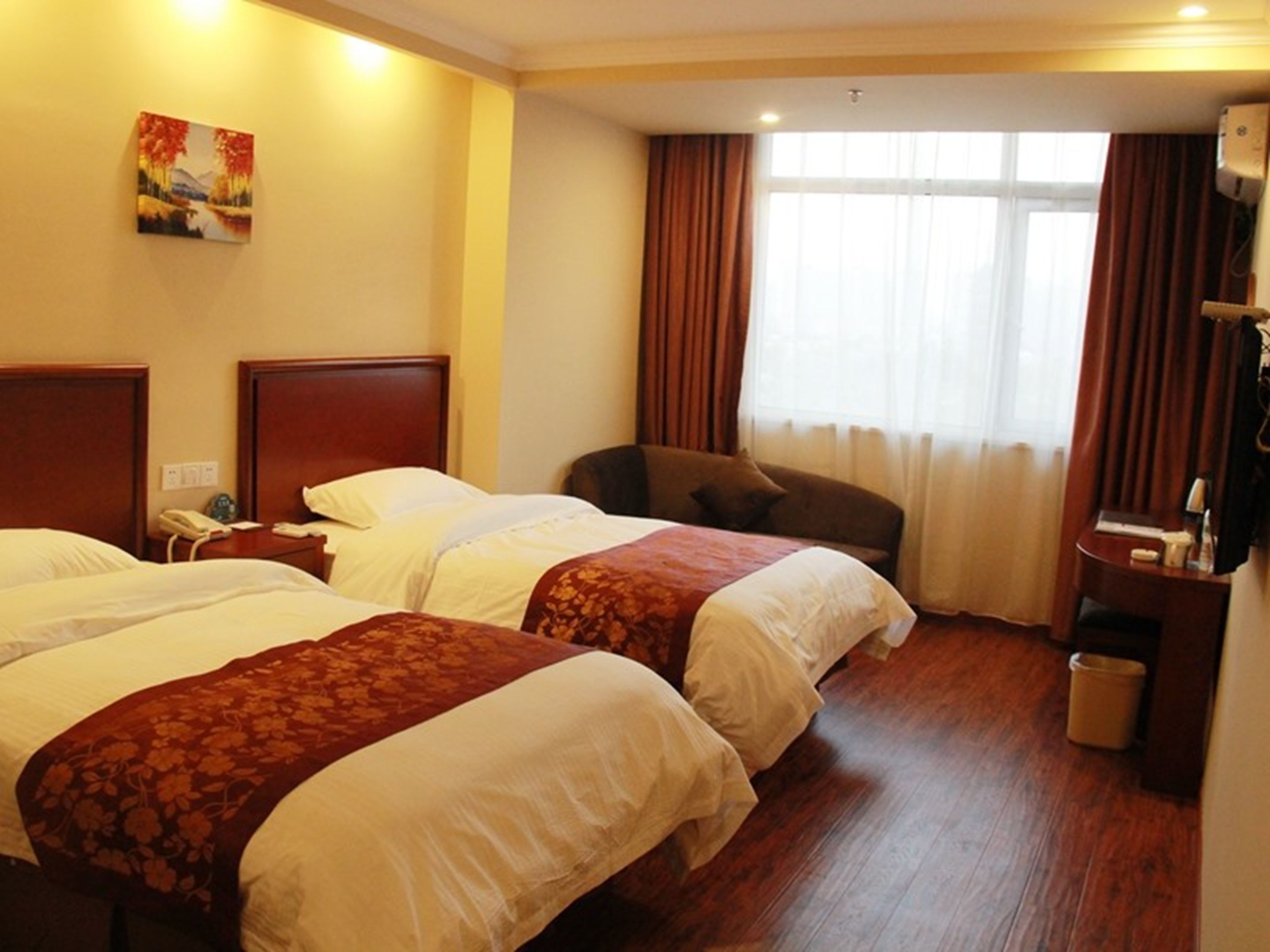 A hotel room with two beds, a desk, a chair, and a large window with curtains.
