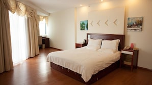 Una habitación de hotel con una cama grande, suelo de madera, un escritorio y una silla.