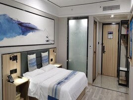 Una habitación de hotel moderna con una cama grande, mesitas de noche, un teléfono en la pared y un cuadro.