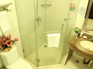 Ein Badezimmer mit einer Duschkabine, einem Waschbecken mit Granitplatte und einer Toilette mit einer dekorativen Vase.