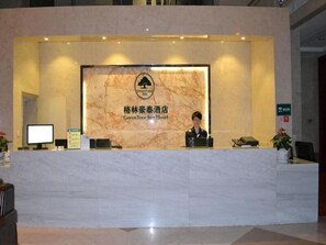 A reception desk at the GreenTree Inn with a marble backdrop, a monitor, and a signboard. - GreenTree Inn Shaoxing Keqiao Xingyue Road Zhongqing Building Hotel (Shaoxing)