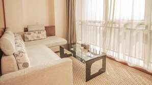 A modern living room with a sofa, a glass coffee table, and sheer curtains. - GreenTree Inn Shaoxing Keqiao Xingyue Road Zhongqing Building Hotel (Shaoxing)