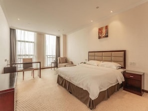 Une chambre d’hôtel avec un grand lit, un bureau, une chaise et une fenêtre avec des rideaux.