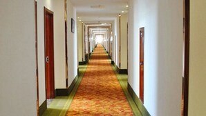 A long, carpeted hallway with doors on both sides, leading to multiple rooms. - GreenTree Inn Yancheng Economic Development Zone Management Committee Express Hotel (Yancheng)