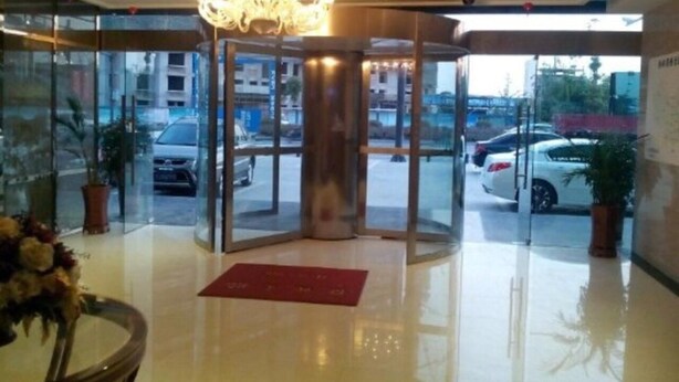 A hotel lobby with a revolving door, a chandelier, and a red mat on the floor. - GreenTree Inn Yancheng Economic Development Zone Management Committee Express Hotel (Yancheng)