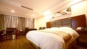 A hotel room with a large bed, a desk with a chair, a television, and a window with curtains. - GreenTree Inn Xuancheng Ningguo City East Ningyang Road RT Mart Express Hotel (Xuancheng)