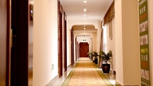 A hotel corridor with a carpeted floor, wooden doors, and potted plants. - GreenTree Inn Xuancheng Ningguo City East Ningyang Road RT Mart Express Hotel (Xuancheng)