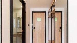 Un pasillo con una puerta de madera, una puerta de cristal y una estantería de metal.