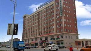 Un hotel de varios pisos con fachada roja, múltiples ventanas y un cartel que indica que es un Green Tree Hotel.
