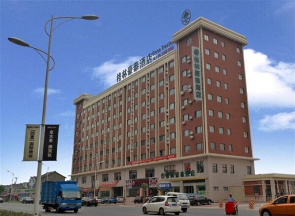 A multi-story hotel with a red facade, multiple windows, and a sign indicating it is a Green Tree Hotel.