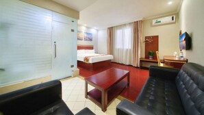 Una habitación de hotel con cama, sofá, mesa, televisor y armario.