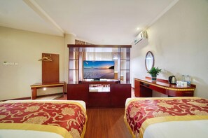 Une chambre d’hôtel avec deux lits, un bureau, une télévision, un miroir et une vue sur la plage.