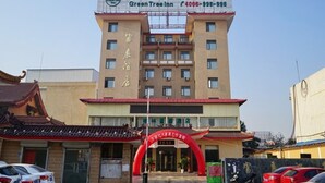 Un hotel con un cartel que dice "Green Tree Inn" y un número de contacto.