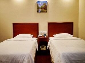 A hotel room with two single beds, wooden headboards, white bedding, a bedside table with a lamp, a phone, and a painting of a landscape. - GreenTree Inn JiangSu XuZhou Pizhou Railway Station Jiefang West Road Business Hotel (Xuzhou)