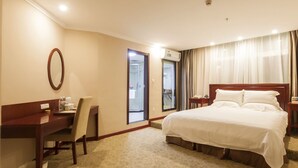 Une chambre d’hôtel avec un lit, un bureau, une chaise, un miroir et une porte de salle de bain.