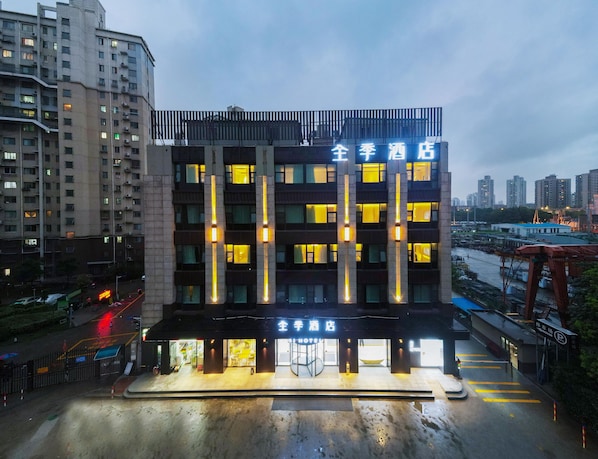 Un hotel de varios pisos con líneas verticales iluminadas y señalización que indica que es un hotel.