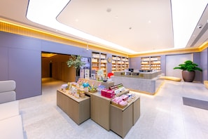 Un espacio comercial moderno con un mostrador central, estanterías de exhibición y zonas de estar.