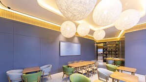 A modern library with round tables, green chairs, and a large bookshelf. - Greentree Inn Site South Yanggao Road Subway Stati (Shanghai)