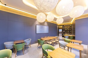 Una biblioteca moderna con mesas redondas, sillas verdes y una amplia estantería.
