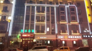 Ett hotell med flera våningar, väl upplysta skyltar och en framträdande filial till banken ICBC.