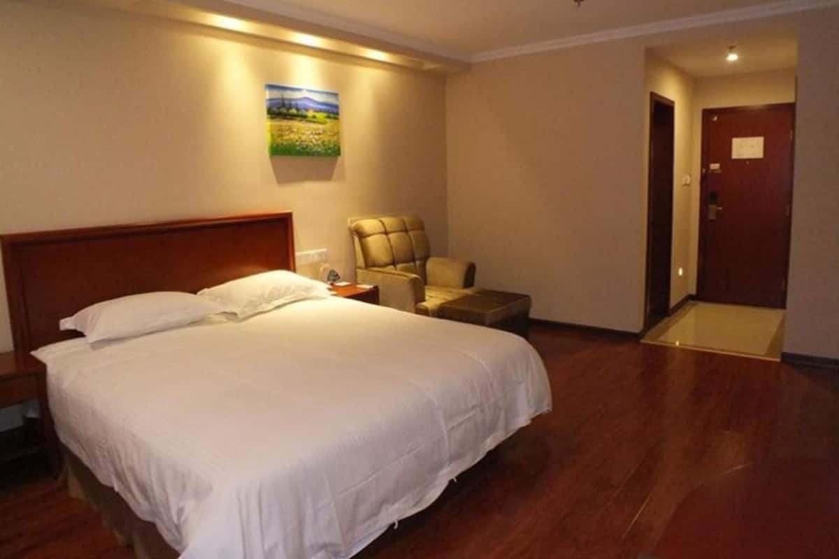 A hotel room with a large bed, a chair, a nightstand, and a door.