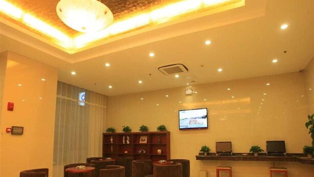 En hotellobby med en receptionsdisk, en tv och flera runda sittgrupper.