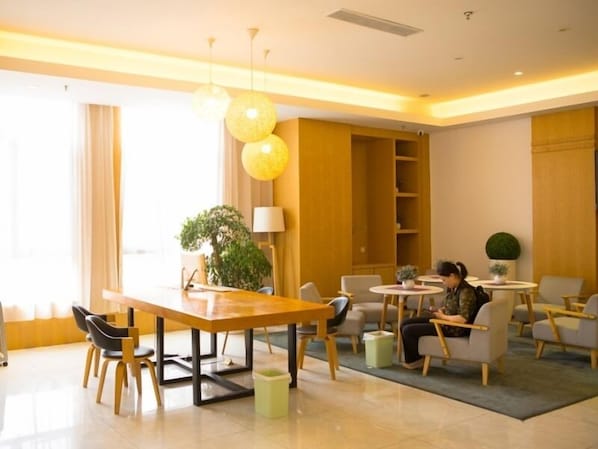 Un hall d’hôtel moderne avec un comptoir d’accueil en bois, des sièges confortables et une grande fenêtre agrémentée de rideaux.